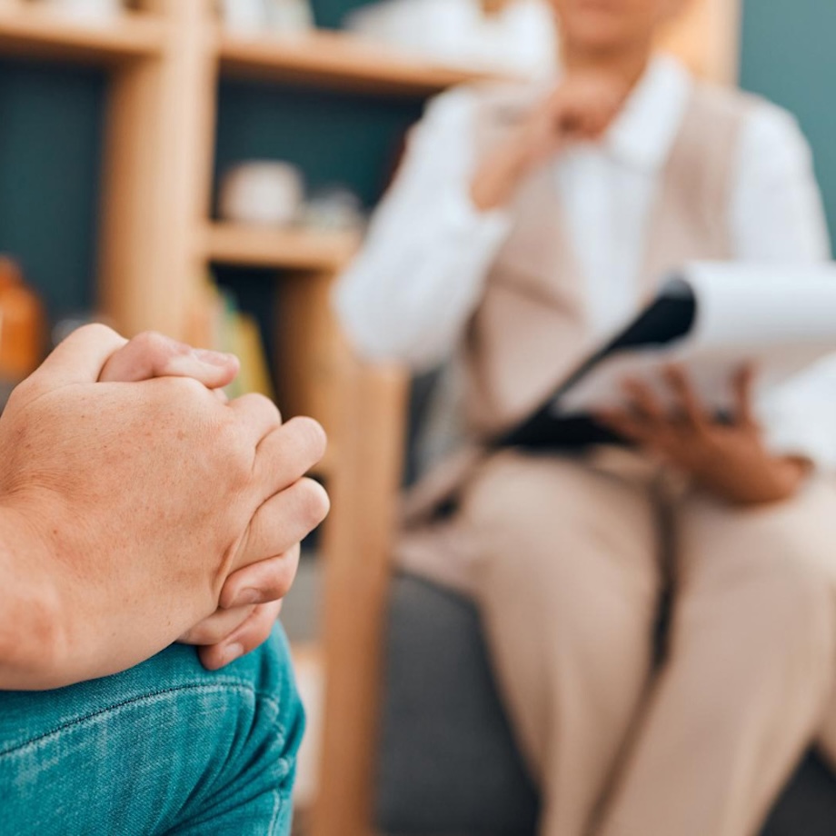 Colloquio di accompagnamento: mani intrecciate in primo piano, professionista in ascolto